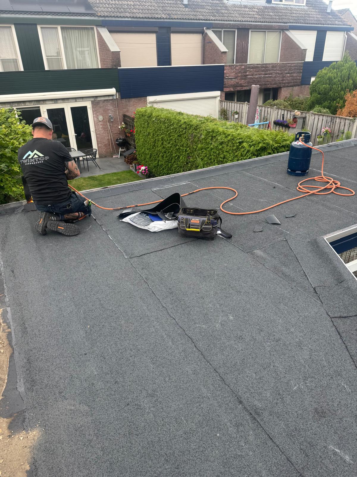 Twintop dakdekker brengt bitumen aan langs de dakrand in Nijmegen