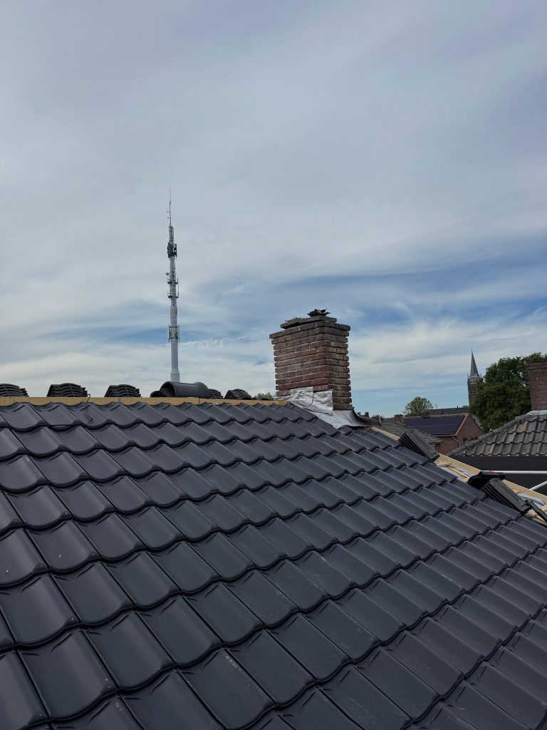 Nieuw antracieten pannendak na de dakrenovatie in Venray, met vernieuwde loodaansluiting bij de schoorsteen